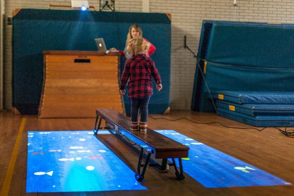 Kind speelt met technologie in gymzaal