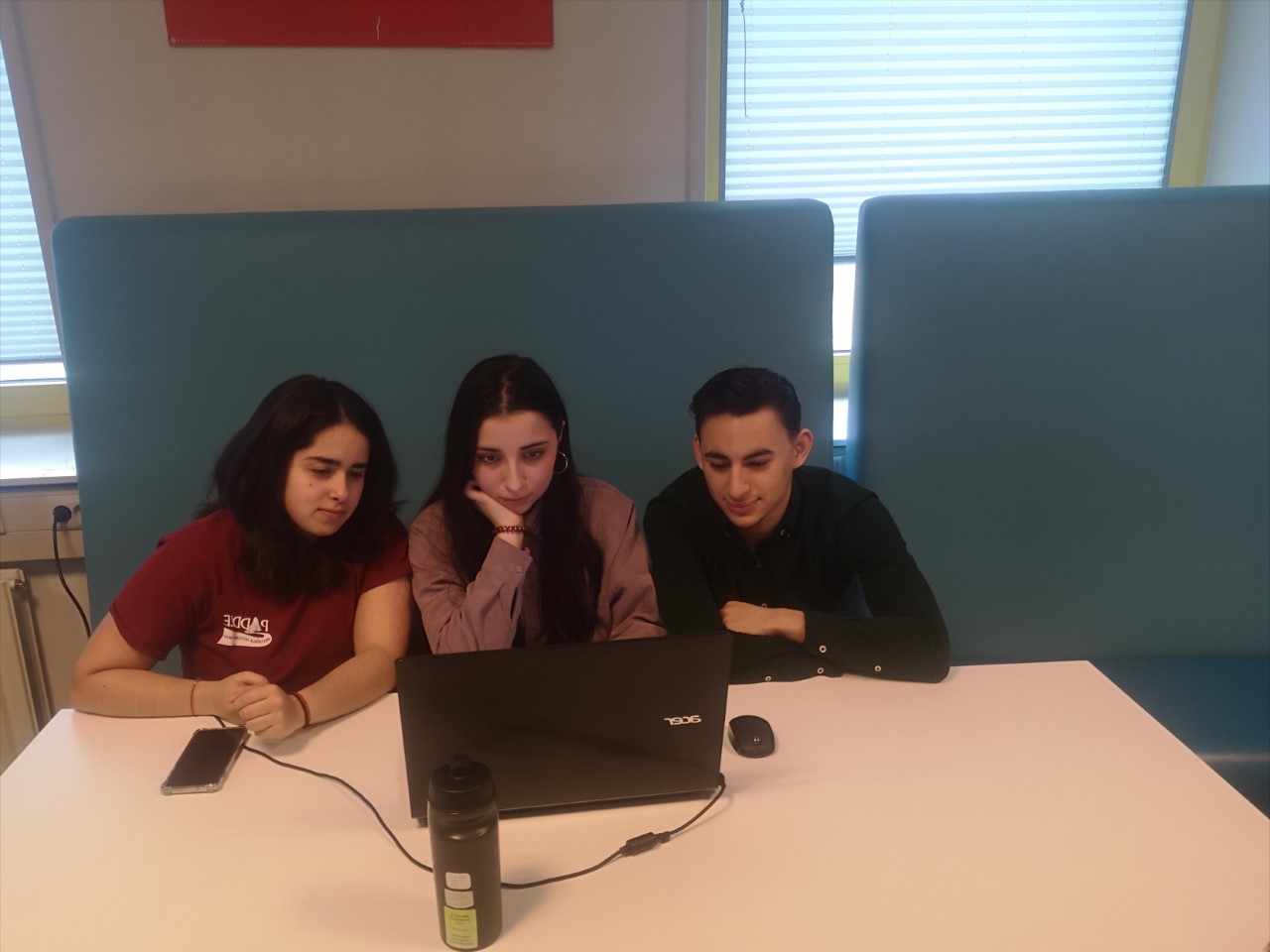 Three students behind a laptop