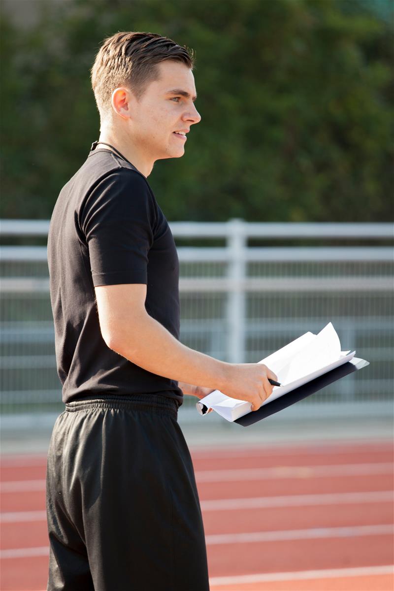 Student met papieren in hand op atletiekbaan