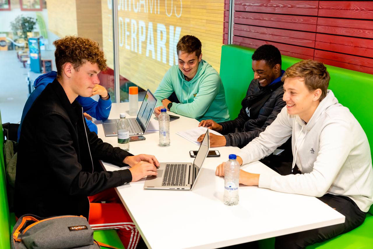 Jonge studenten die achter een laptop zitten