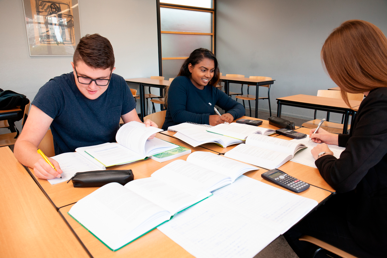 Studenten aan tafel met veel papieren