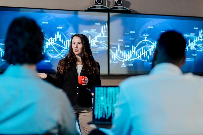 Student staat voor de klas en presenteert data op schermen.