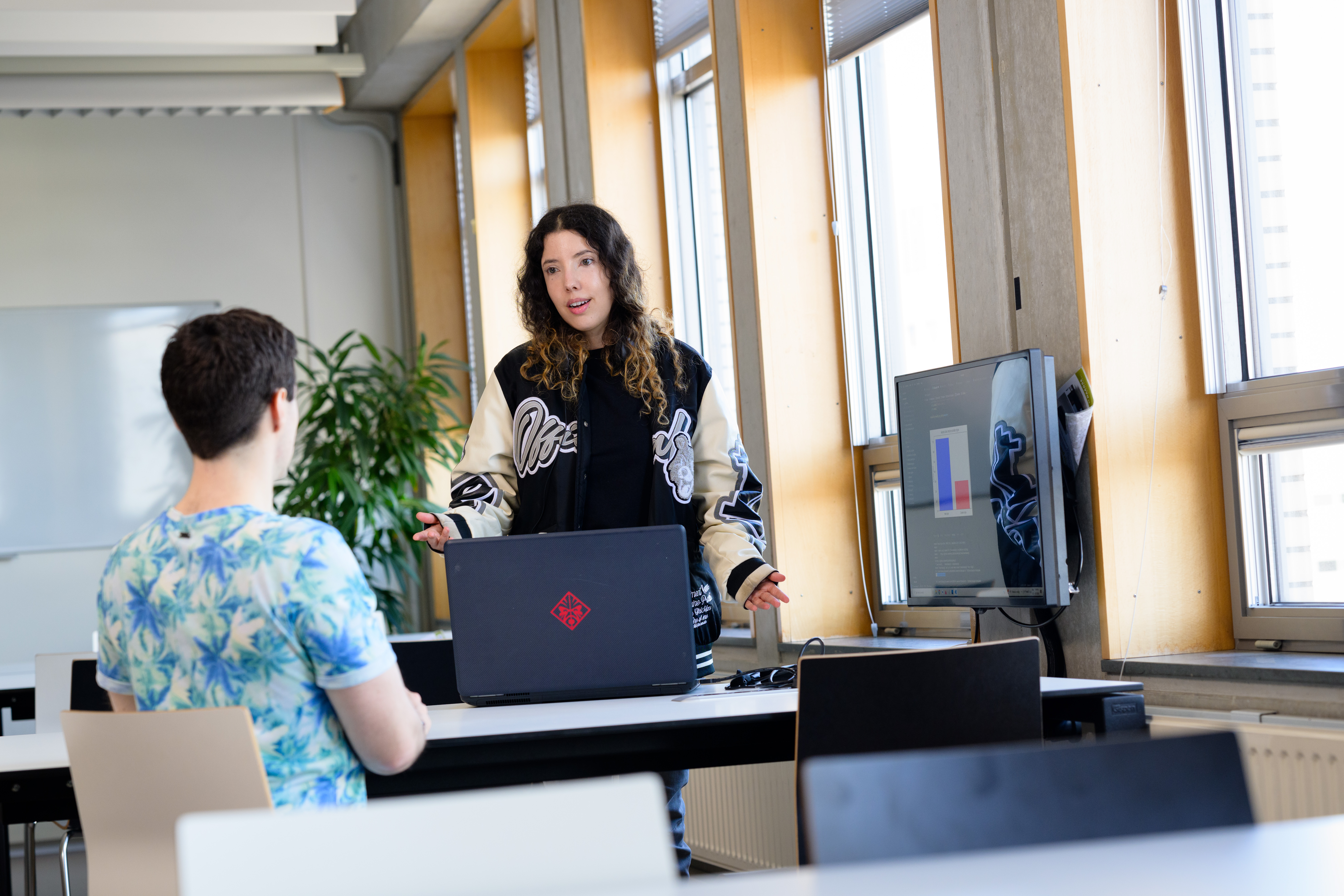 Twee studenten werken samen aan tafel met laptop