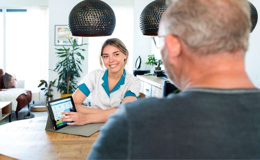 Zorgmedewerker laat iets op de laptop zien aan client