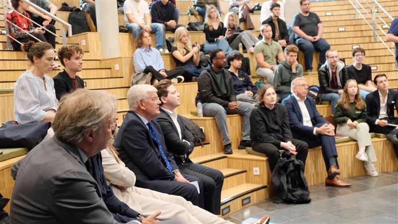 Groep mensen die zit op de bankjes van de collegezaal