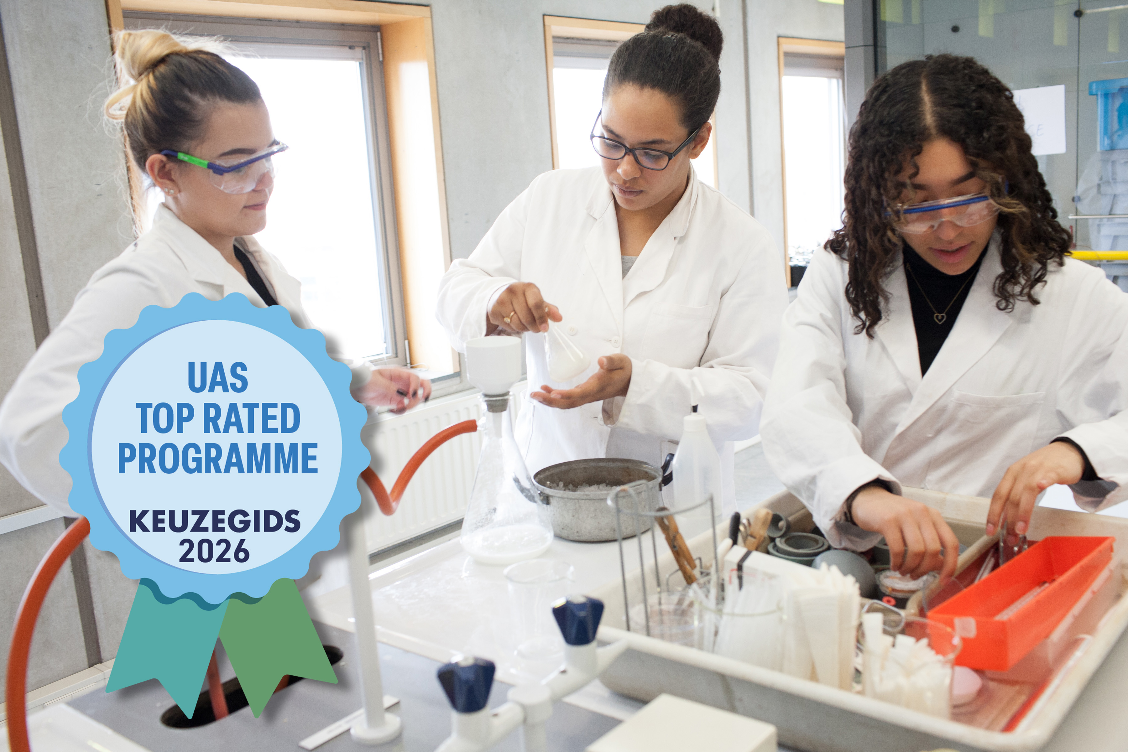 Three students in lab coats working with laboratory equipment; badge reading "UAS Top rated programme Keuzegids 2026" in the foreground.