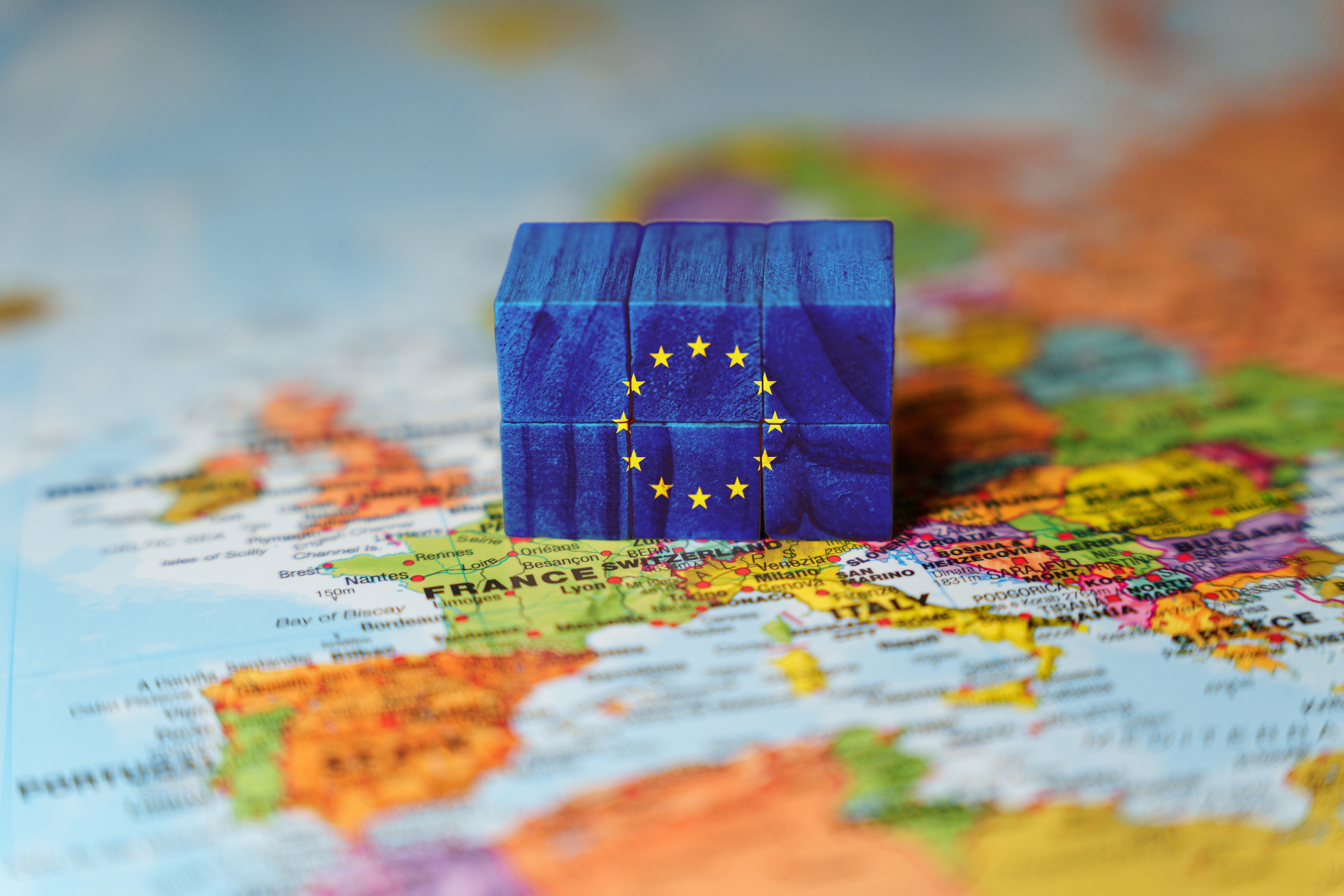 A world map with a european flag shaped in a cube.