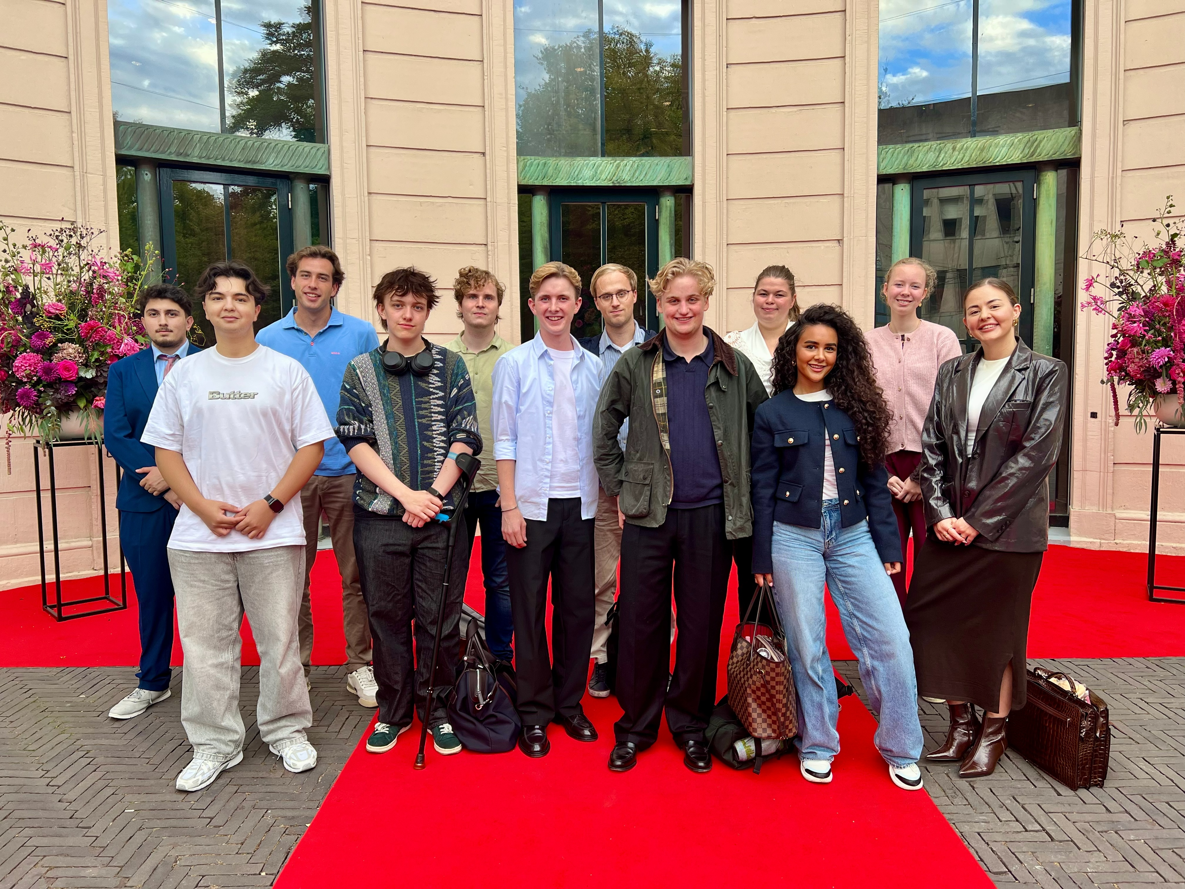 Haagse Hogeschoolstudenten poseren op de rode loper voor een monumentaal gebouw tijdens een bijeenkomst rond Prinsjesdag.