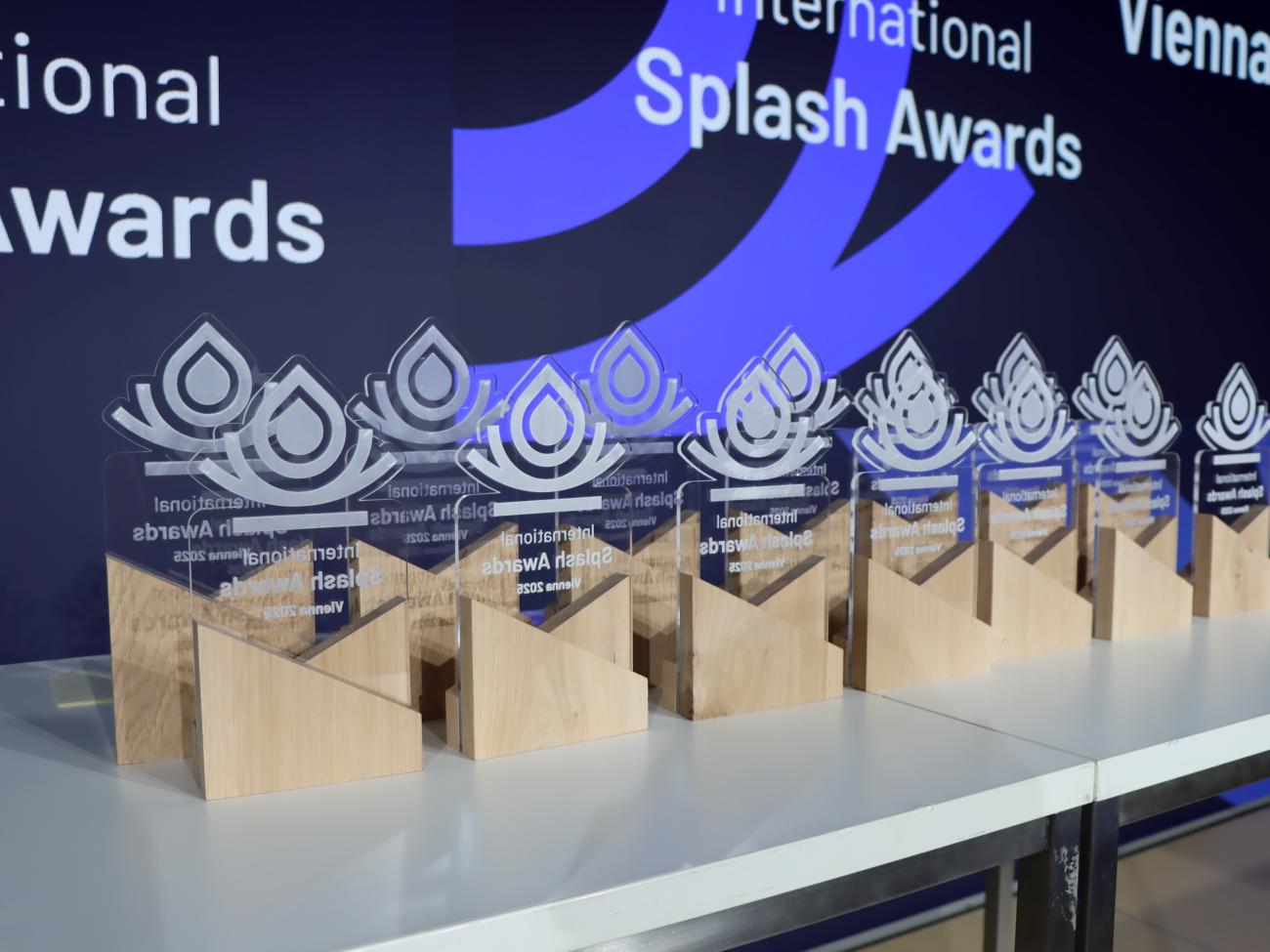 Een rij International Splash Awards-trofeeën staat uitgestald op een tafel tijdens de prijsuitreiking.