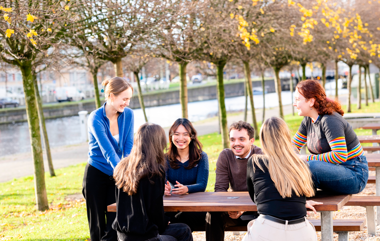 Groep studenten buiten aan tafel